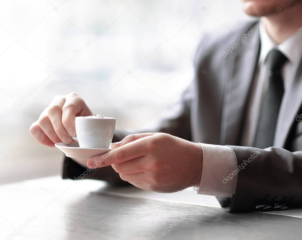 close up.businessman holding a Cup of coffee sitting at his Desk