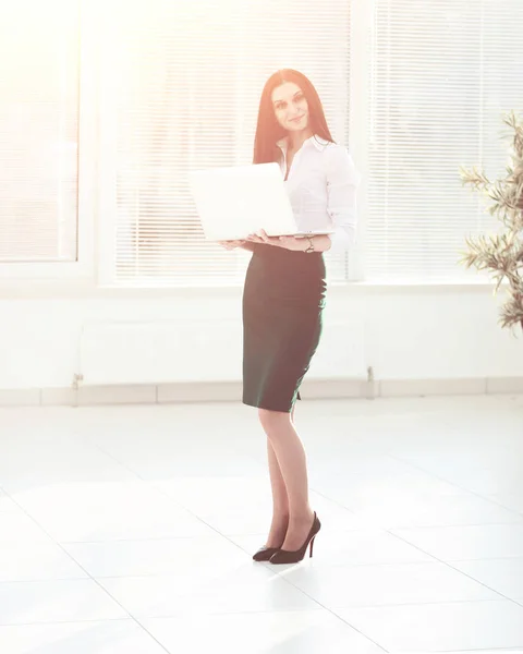 Женщина-ассистент с открытым ноутбуком, стоя в офисе — стоковое фото