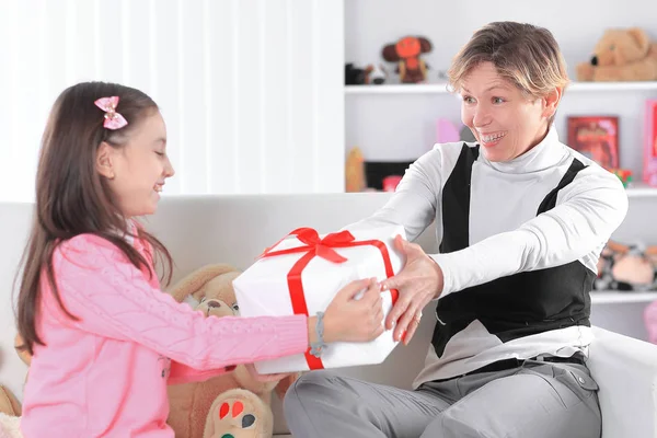 Abuela le da a su nieta una caja con un regalo — Foto de Stock