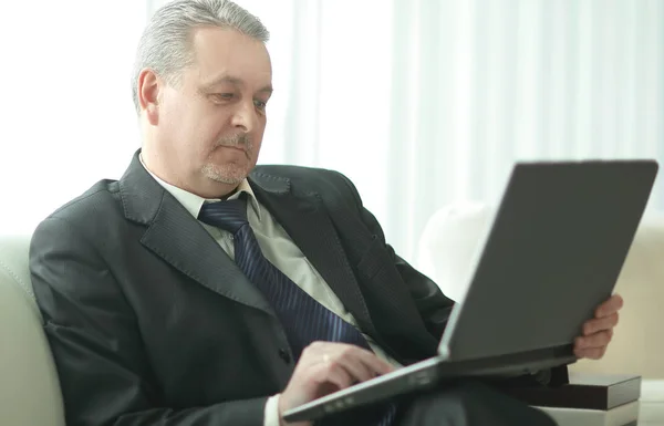 Erfolgreicher Geschäftsmann sitzt mit Laptop in Büro-Lobby — Stockfoto