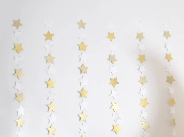 Christmas lights gold stars are burning on the white wall. — Stock Photo, Image