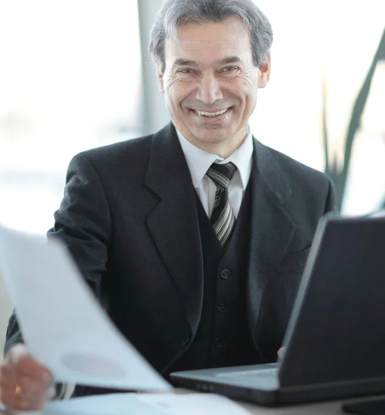 Sorridente empresário sênior sentado em sua mesa — Fotografia de Stock