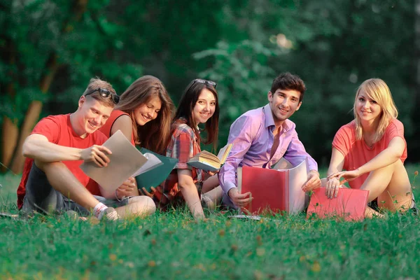 Groupe d'amis étudiants assis sur l'herbe dans le parc — Photo