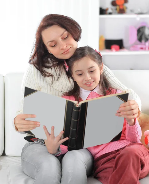 Portrait of mother and daughter with a book sitting on the couch.photo with copy space — Stock Photo, Image