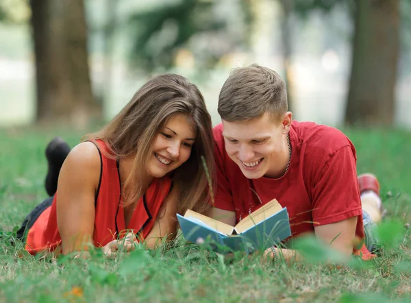 Kilku studentów, leżąc na trawie w parku i czytanie książek — Zdjęcie stockowe