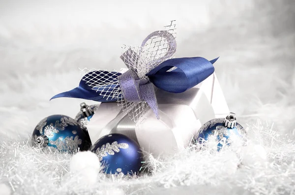 Regalo de Navidad y bolas azules de Navidad en un respaldo blanco festivo — Foto de Stock