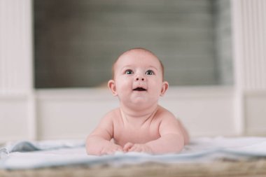 Güzel bebek yerde yatıyor ve şaşkınlıkla yukarı bakıyor.