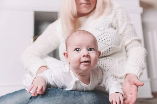 Mãe com bebê sentado perto da lareira em uma sala de estar aconchegante — Fotografia de Stock