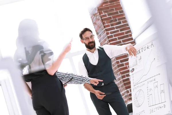 group of employees discussing financial performance while standing in the office