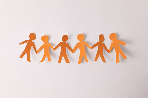 Четыре бумажных человека берут друг друга за руки
