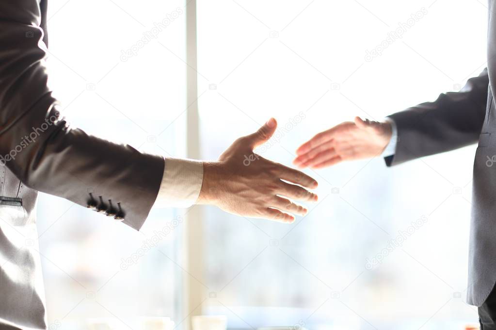 close up. handshake business people standing near the window in the office