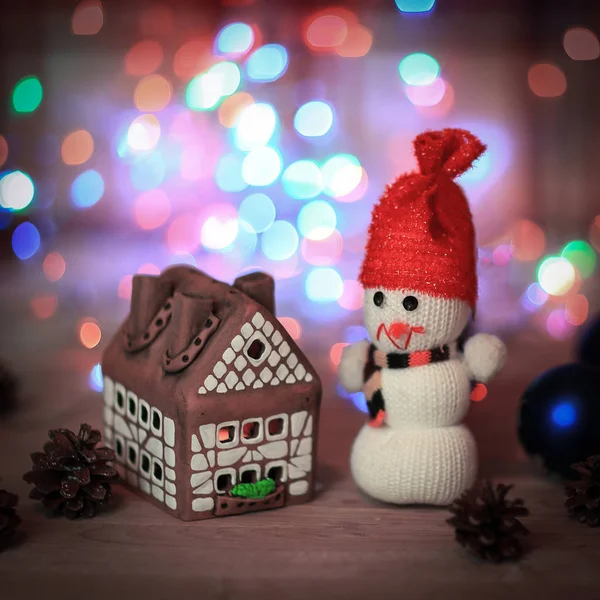 Speelgoed sneeuwpop en peperkoek huis aan de kersttafel — Stockfoto