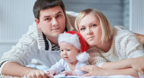 Pais e um bebê bonito em um chapéu de Papai Noel — Fotografia de Stock