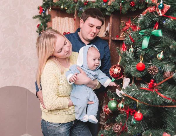 Padres felices y su bebé de pie cerca del árbol de Navidad — Foto de Stock