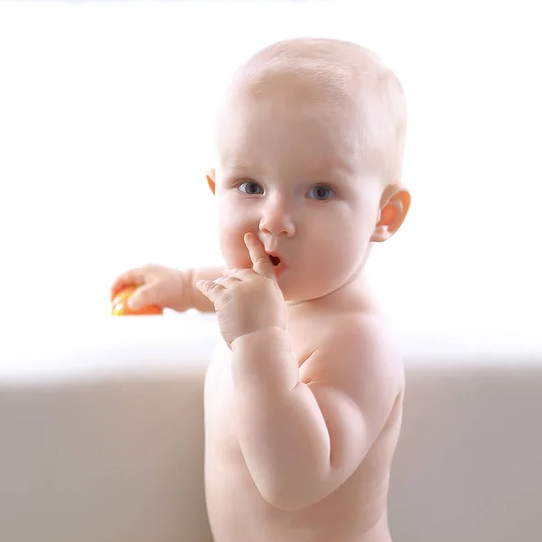 Joli bébé avec une tranche de mandarin est sur le canapé — Photo