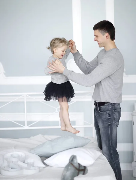 Papá juega con su hija en la cama en el dormitorio — Foto de Stock