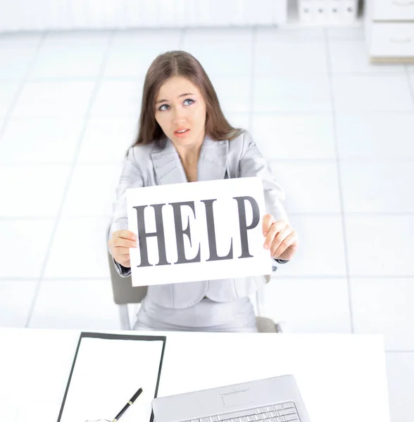 Business woman holding a sign saying help ,sitting behind a Desk — Stock Photo, Image