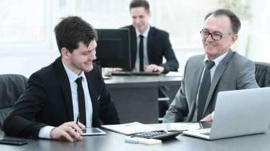 patron ve çalışanın ofis masasında oturan belge tartışıyor.