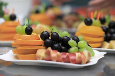 yakın up.Apples, portakal ve üzüm bir plaka üzerinde