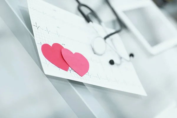 Stethoscoop, cardiogram en twee rode papier hart op tafel. — Stockfoto