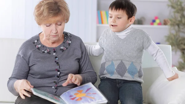 Portrait of grandmother and grandson reading a book in the nursery — Stock Photo, Image