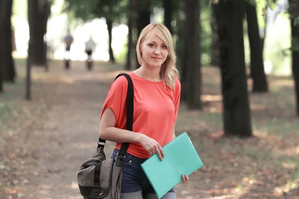 Estudiante exitosa con una bolsa y un portapapeles en el fondo del Parque —  Fotos de Stock