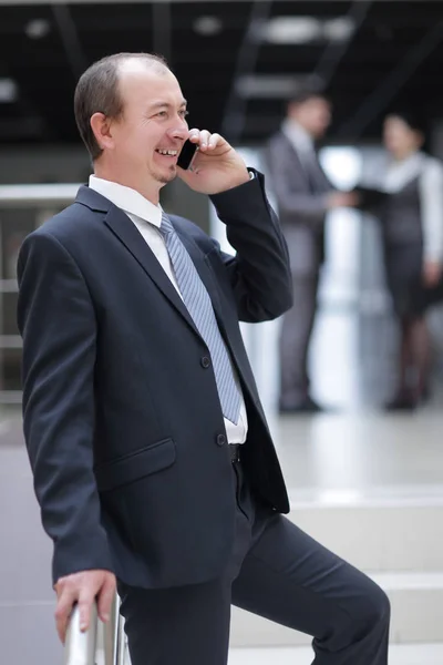 Улыбающийся бизнесмен разговаривает по мобильному телефону в офисе — стоковое фото