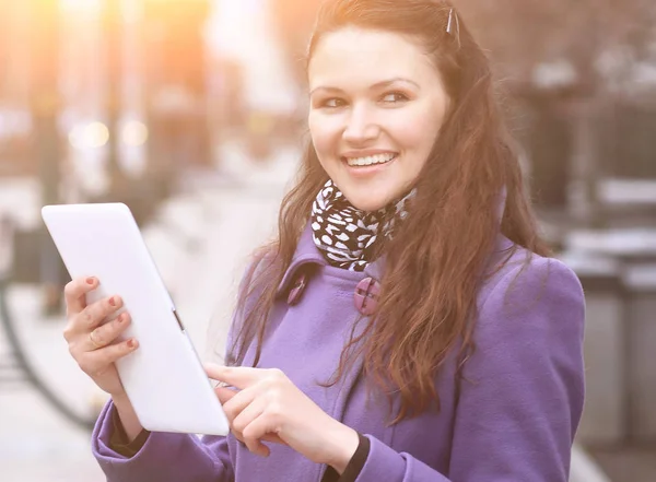 Jonge vrouw met digitale tablet op de achtergrond wazig stad — Stockfoto