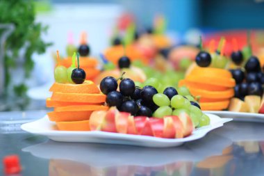 yakın up.Apples, portakal ve üzüm bir plaka üzerinde