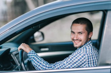 yan görünümü. bir arabanın direksiyonuna oturan bir genç adam