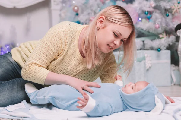 Mãe abraça seu bebê perto da árvore de Natal . — Fotografia de Stock