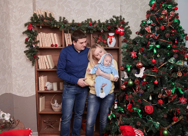 Pais felizes e seu bebê em pé perto da árvore de Natal — Fotografia de Stock