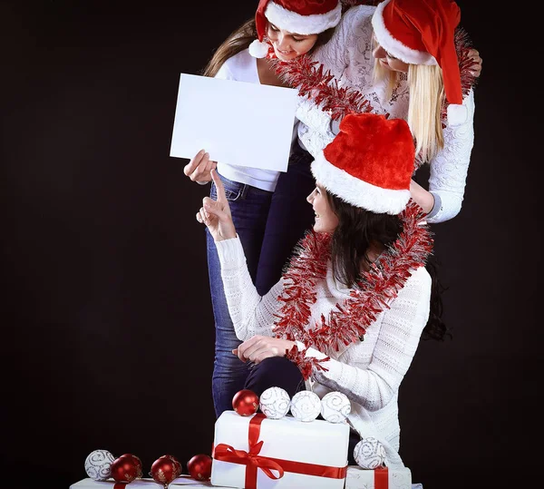 Três meninas no traje de Papai Noel mostrando folha em branco — Fotografia de Stock