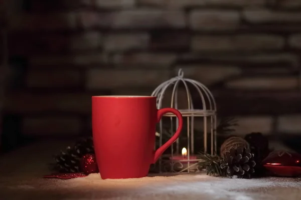 Closeup.red Christmas Cup and the candle on the holiday table — Stock Photo, Image