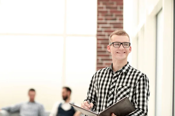 Employé souriant avec un presse-papiers debout dans le bureau — Photo