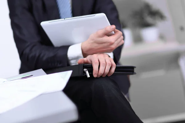 Närbild. Affärsman med läderportföljer med digital tablett sitter på en kontorsstol — Stockfoto