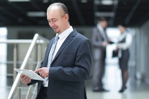Бизнесмен читает текст на цифровом планшете, стоящем в офисе . — стоковое фото
