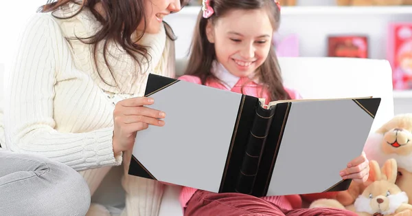 Charming mother and daughter reading a book sitting on the couch.photo with copy space — Stock Photo, Image