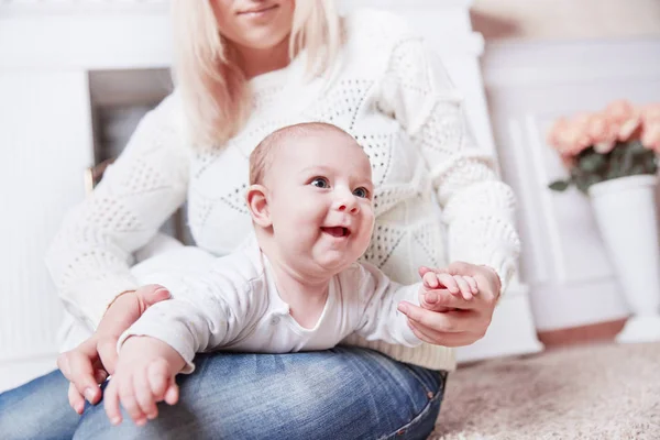 Mãe com bebê sentado perto da lareira em uma sala de estar aconchegante — Fotografia de Stock