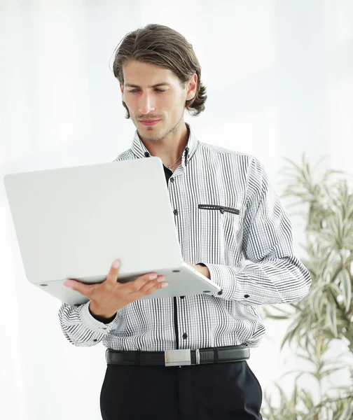 Poważny biznesmen pracę na laptop stoi w biurze. — Zdjęcie stockowe