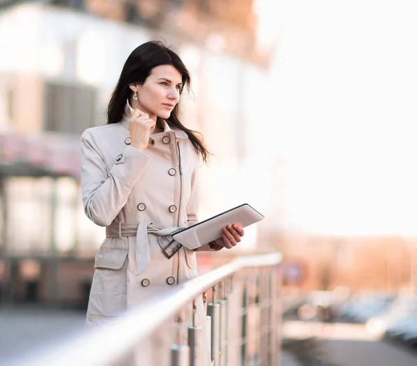 Mujer de negocios moderna trabajando en una tableta digital, de pie junto a un edificio de oficinas — Foto de Stock