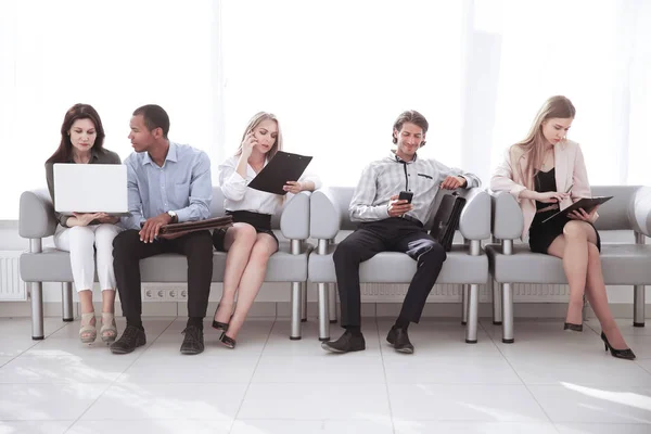 Zespół firmy studiując dokumenty robocze, siedząc w holu urzędu. — Zdjęcie stockowe