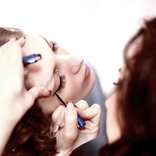 Belle femme avec pinceau de maquillage près de son visage sur un fond blanc . — Photo