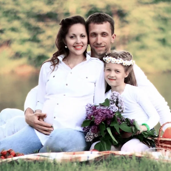 Glücklicher Vater einer Tochter und schwangere Mutter bei einem Picknick. — Stockfoto