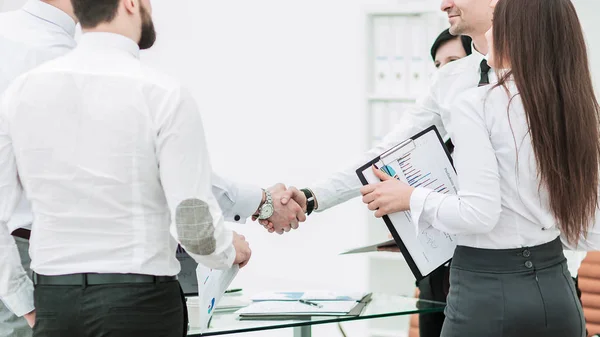 Apretón de manos de los socios comerciales sobre los antecedentes de los trabajadores de oficina — Foto de Stock