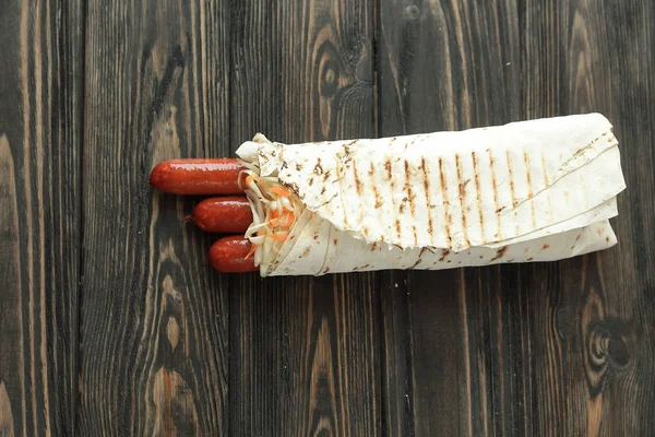 Пряные сосиски в пита-хлебе на деревянном фоне. — стоковое фото