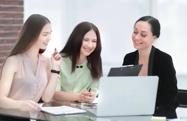 Geschäftsfrau diskutiert ein Dokument mit einer Mitarbeiterin, wenn sie sich einen Schreibtisch im Büro teilen — Stockfoto