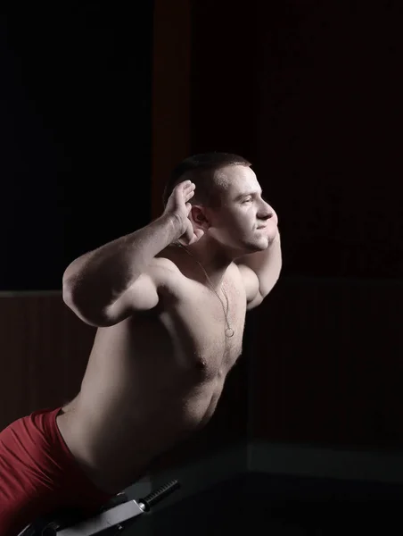 Jovem homem bonito executa exercícios esportivos para fortalecer os músculos — Fotografia de Stock