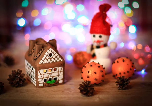 Speelgoed sneeuwpop en peperkoek huis aan de kersttafel — Stockfoto