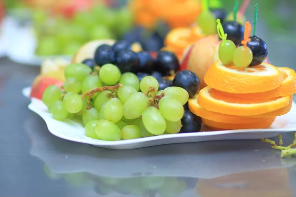 Close up.plate with grapes and oranges on blurred background — Stock Photo, Image